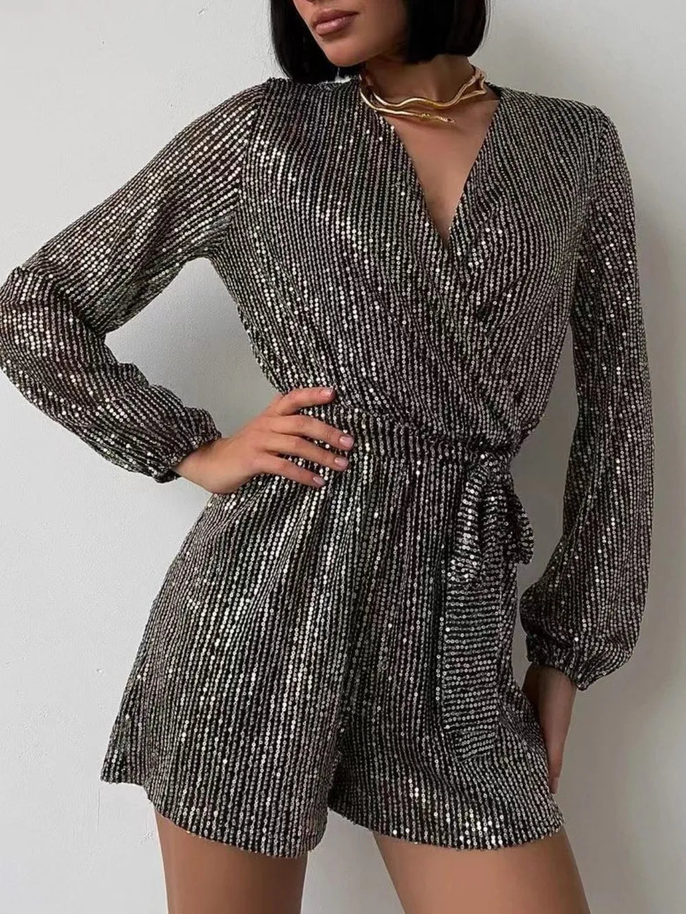 Dark green sequin long sleeve romper by Marigold Collections Australia, featuring a surplice neckline and tie waist for elegant evening wear.