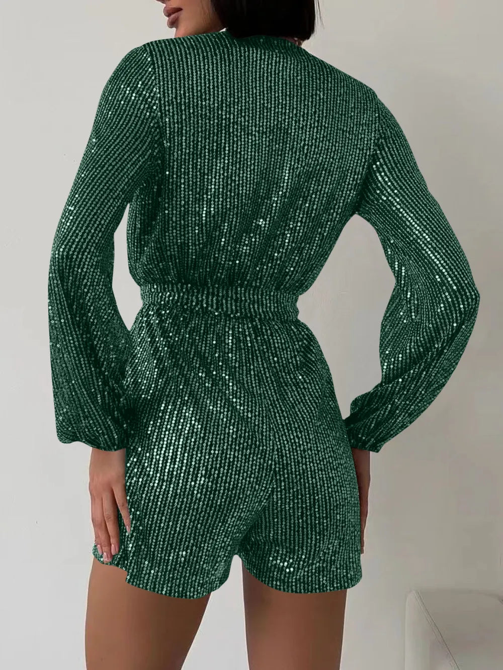 Dark green sequin long sleeve romper by Marigold Collections Australia, featuring a surplice neckline and tie waist for elegant style.